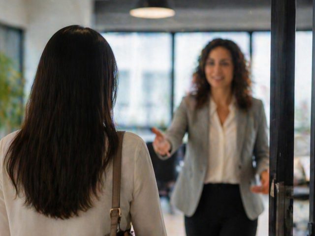 Manager extending a welcoming hand toward an employee returning to the office, illustrating a reversed dismissal.