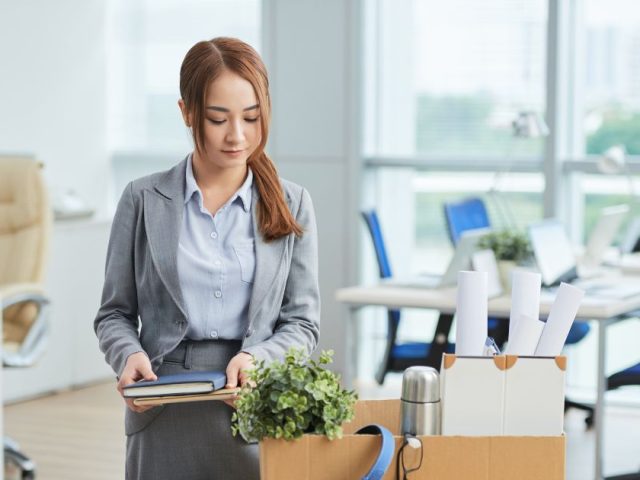 Woman leaving office with a box of belongings after job loss, duty to mitigate explained for dismissed employees in Canada.