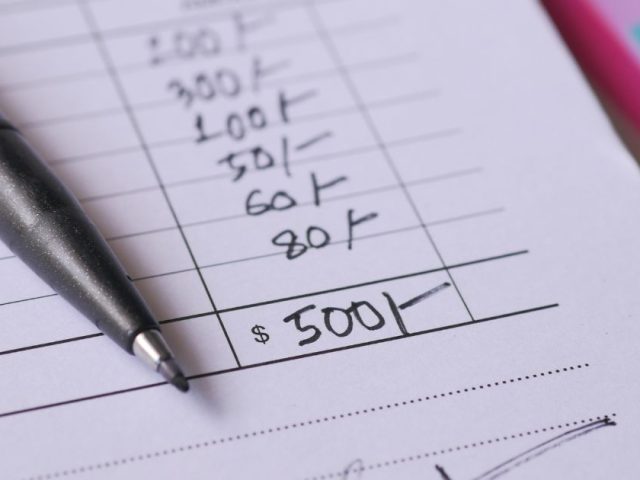Close up of handwritten amounts and pen on paper showing final pay in BC explained for departing employees and employers.