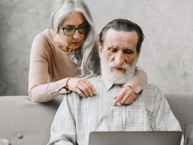 Senior couple reviewing a laptop together at home, retirement age in BC explained and employee rights under provincial law.