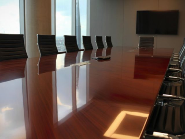 Empty boardroom with long table and city view, collective bargaining labour lawyers representing unions and employers.