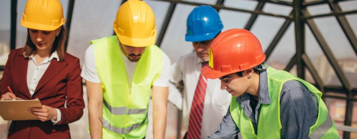 Construction workers in hard hats and safety vests reviewing plans on a building site, representing the BC construction context of the Parolin v. Cressey case.