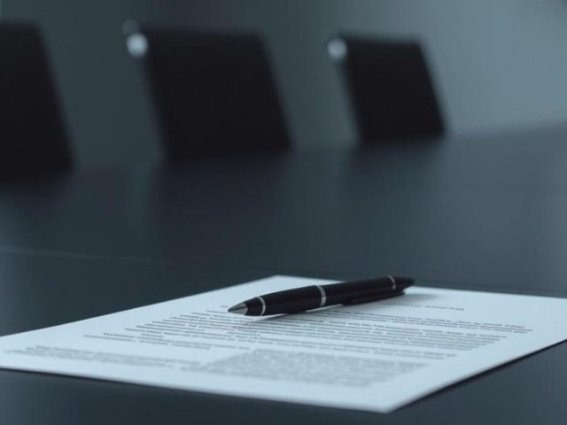 Legal document and pen on a boardroom table, illustrating contract review and employer legal mistakes.
