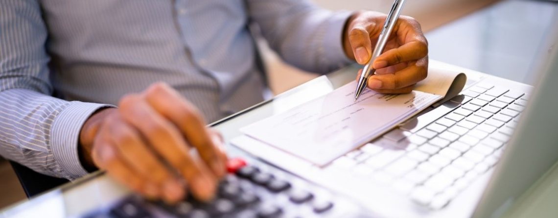 Person using a calculator and reviewing a paycheque, illustrating wage deductions under the Ontario Employment Standards Act.