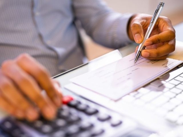 Person using a calculator and reviewing a paycheque, illustrating wage deductions under the Ontario Employment Standards Act.