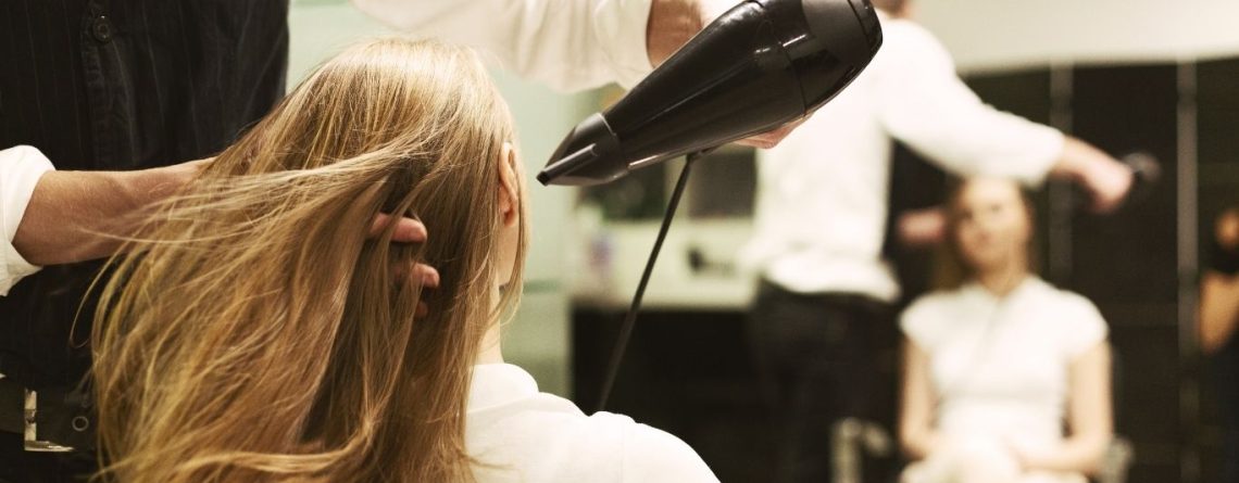 Stylist blow-drying a woman's long hair at a salon, illustrating the Glow Hair Studio resignation case