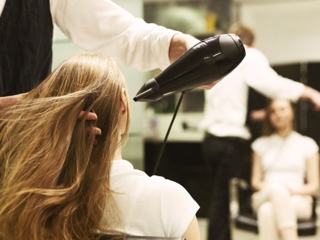 Stylist blow-drying a woman's long hair at a salon, illustrating the Glow Hair Studio resignation case