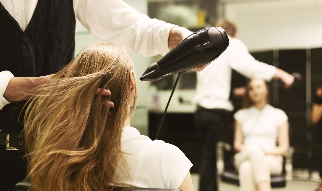 Stylist blow-drying a woman's long hair at a salon, illustrating the Glow Hair Studio resignation case